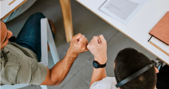 Two co-workers giving each other a fist bump