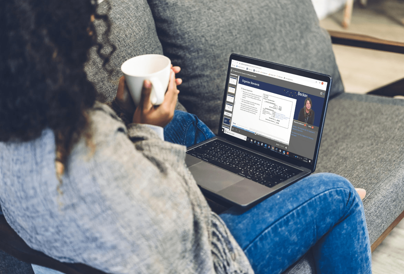 woman holding a coffee mug and watching a video lecture on their laptop